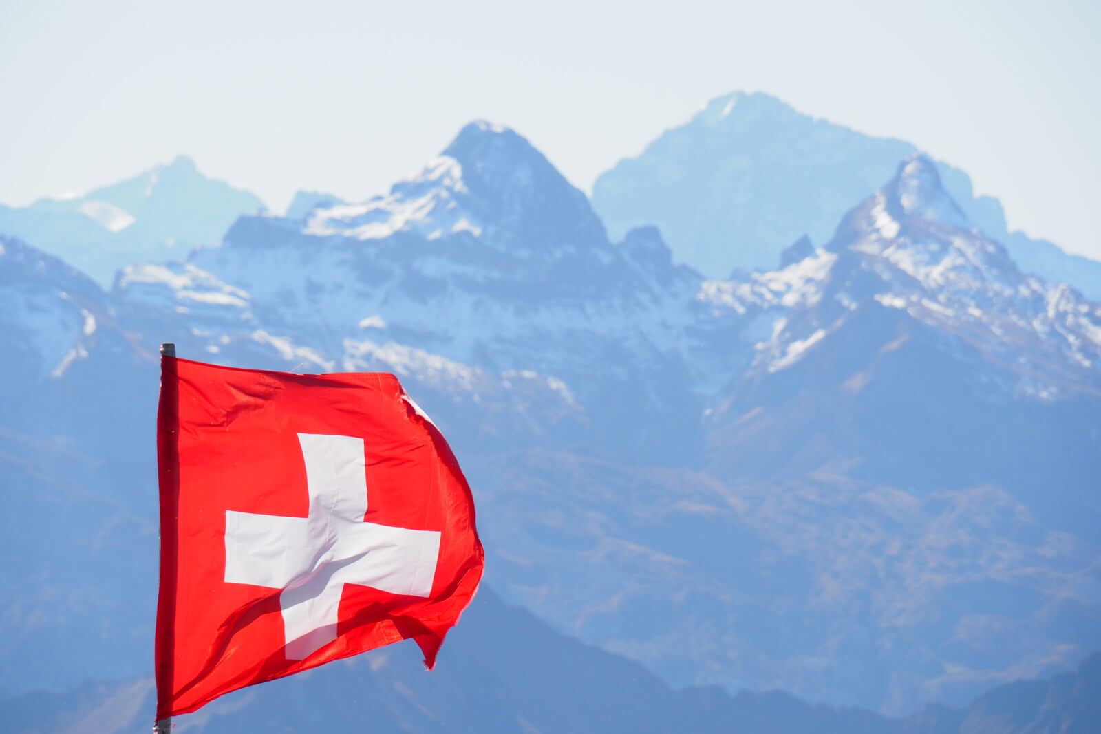 Swiss flag with mountains in the background