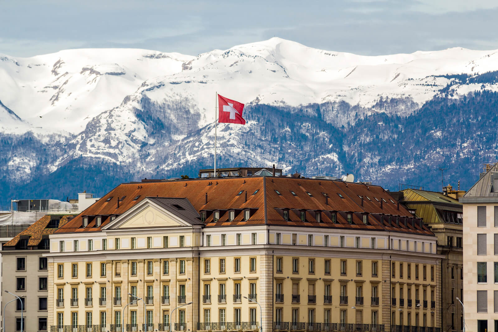 The Geneva City Scape with Snow-Covered Peaks and a Swiss Flag