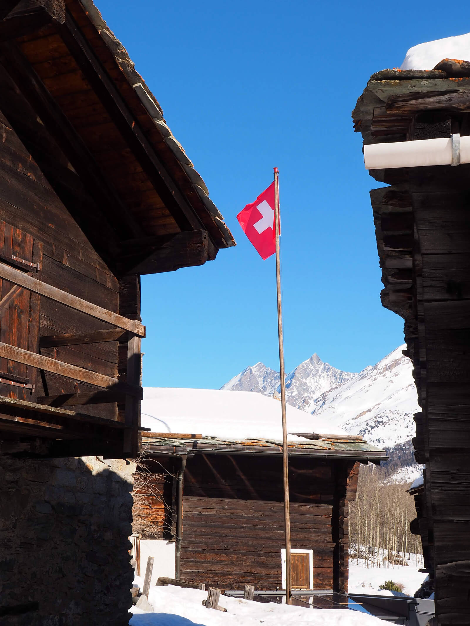 Swiss Flag in a Snow Covered Village in Valais, Switzerland