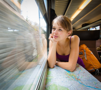 Young female tourist sitting in a Swiss train looking out the window and thinking "Is the Swiss Travel Pass Worth it?" - Swiss Travel Pass reviews, Best travel pass for Switzerland, Switzerland rail pass reviews