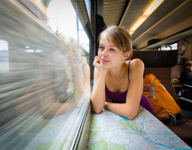 Young female tourist sitting in a Swiss train looking out the window and thinking "Is the Swiss Travel Pass Worth it?" - Swiss Travel Pass reviews, Best travel pass for Switzerland, Switzerland rail pass reviews