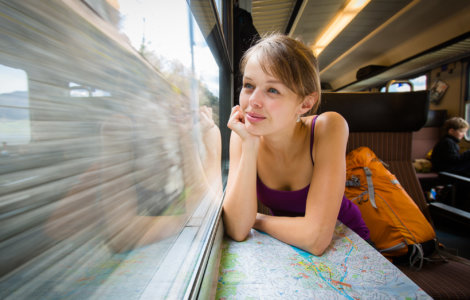 Young female tourist sitting in a Swiss train looking out the window and thinking "Is the Swiss Travel Pass Worth it?" - Swiss Travel Pass reviews, Best travel pass for Switzerland, Switzerland rail pass reviews