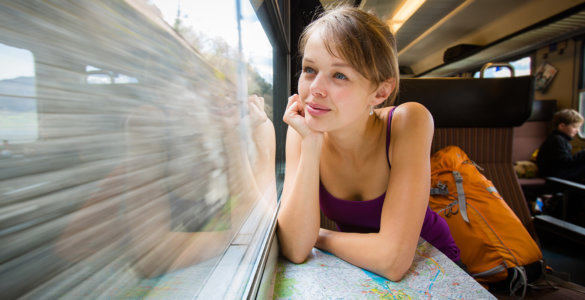 Young female tourist sitting in a Swiss train looking out the window and thinking "Is the Swiss Travel Pass Worth it?" - Swiss Travel Pass reviews, Best travel pass for Switzerland, Switzerland rail pass reviews