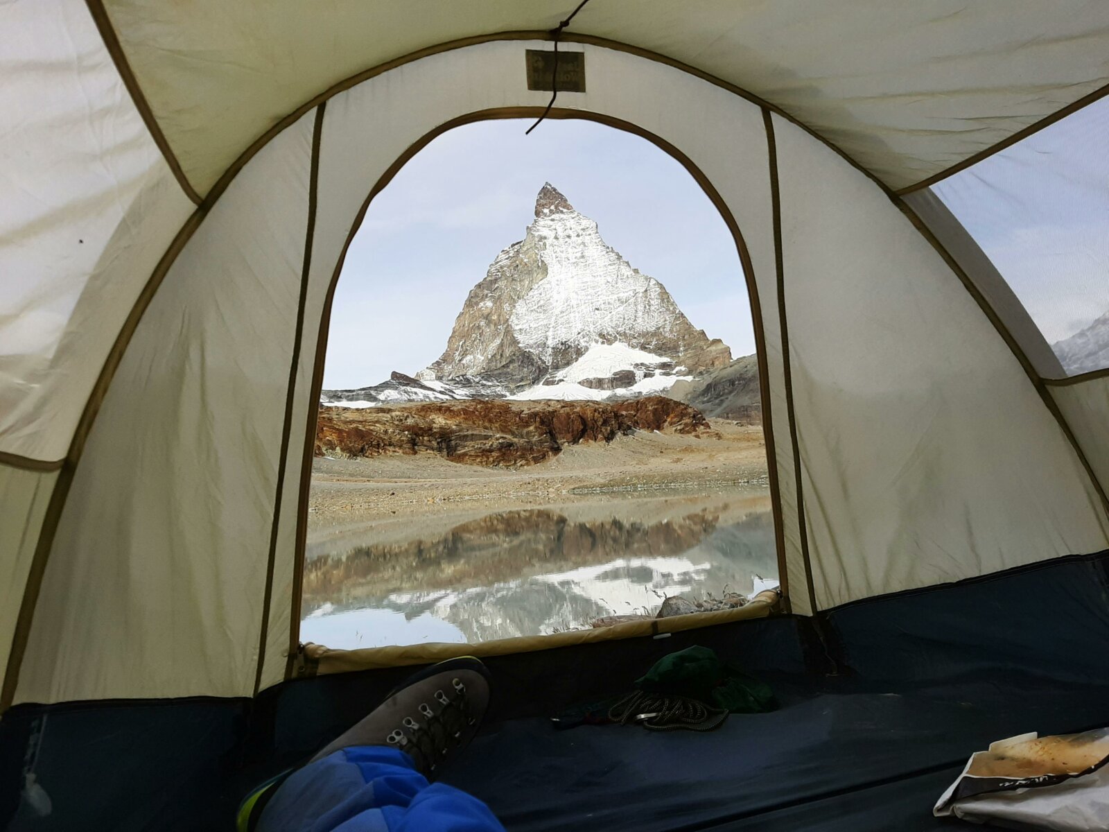 A stunning view of the Matterhorn from inside a tent, reflecting in a serene lake in Zermatt, Switzerland.